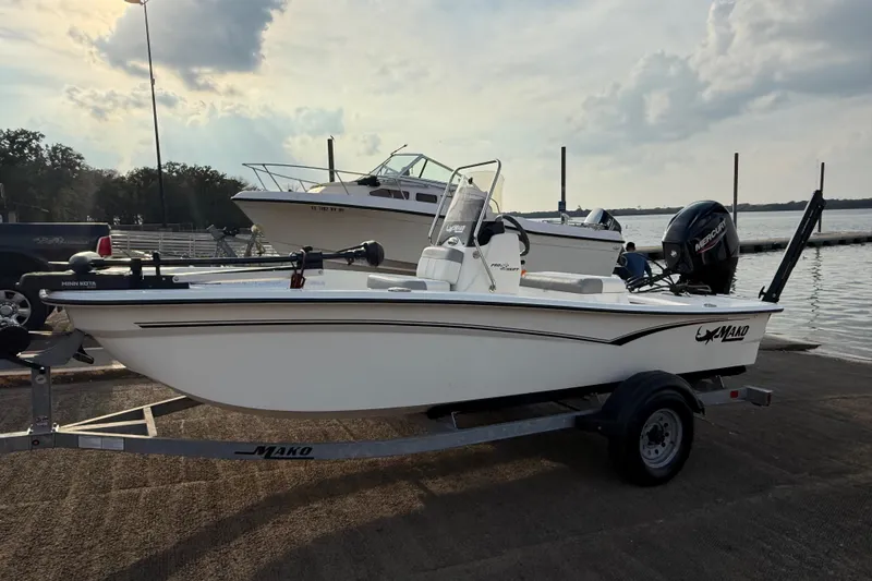 Slide: The Image of 2023 Mako Pro Skiff 15 CC boat on trailer by the water. - 57