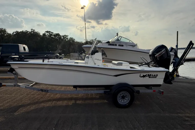 Slide: The Image of 2023 Mako Pro Skiff 15 CC boat on trailer by the water at sunset. - 58