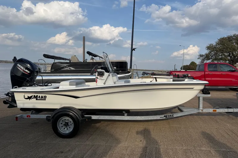 Slide: The Image of 2023 Mako Pro Skiff 15 CC boat on trailer, parked outdoors under cloudy sky. - 70