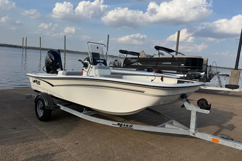 Slide: The Image of 2023 Mako Pro Skiff 15 CC boat on trailer by waterfront, under cloudy sky. - 72