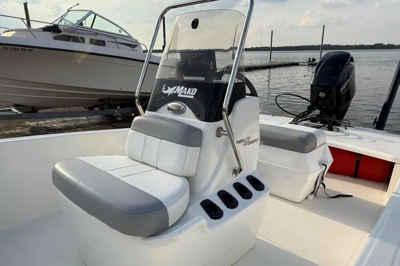 Slide: The Image of 2023 Mako Pro Skiff 15 CC boat on trailer by the water, under a cloudy sky. - 73