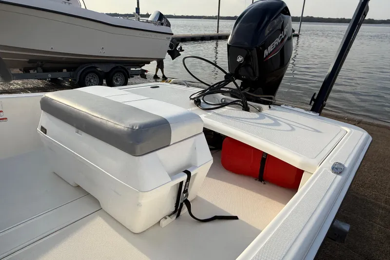 Slide: The Image of 2023 Mako Pro Skiff 15 CC boat interior with seating and console, docked by the water. - 74