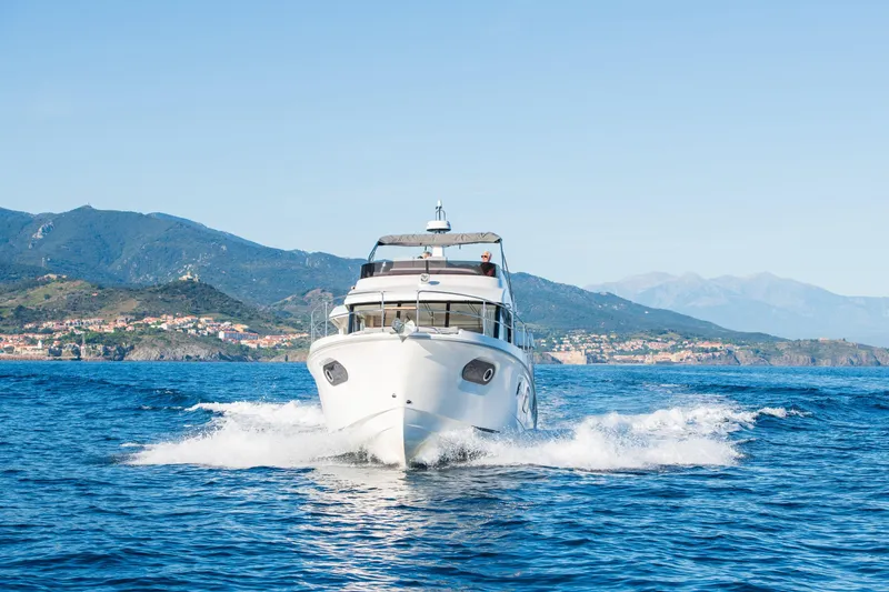 Slide: The Image of 2026 Beneteau Swift Trawler 41 Fly cruising on blue ocean with scenic mountain backdrop. - 17