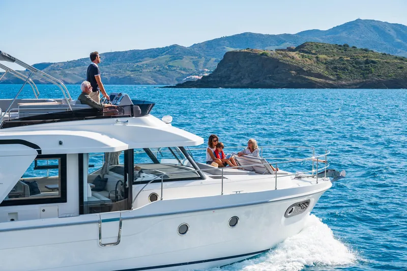Slide: The Image of 2026 Beneteau Swift Trawler 41 Fly cruising with passengers, scenic coastal backdrop. - 22