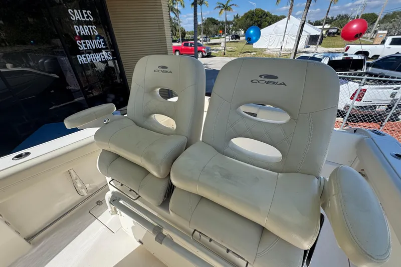 Slide: The Image of 2021 Cobia 262 Center Console boat seats, showroom display with palm trees and balloons. - 11