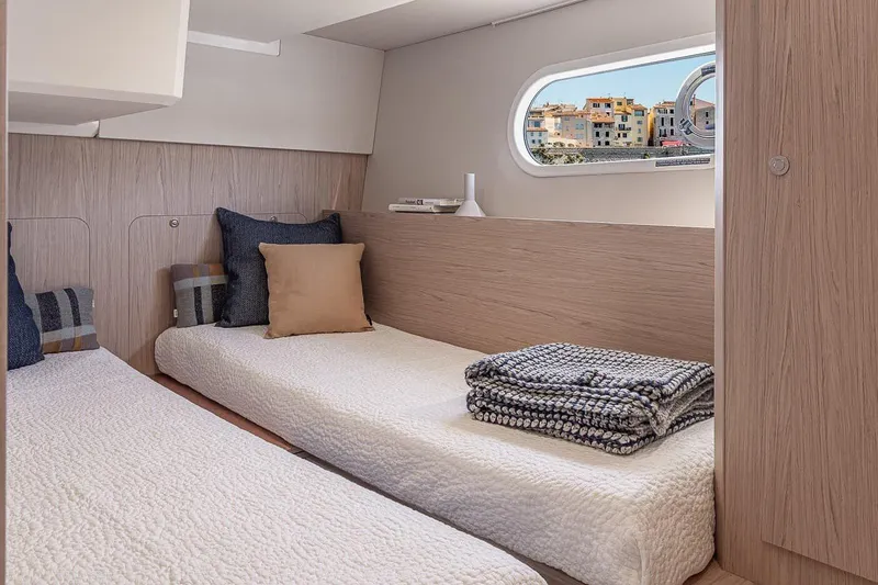 Slide: The Image of 2026 Beneteau Swift Trawler 41 Sedan cabin with twin beds and cozy decor. - 11