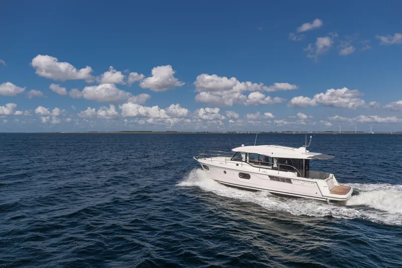 Slide: The Image of 2026 Beneteau Swift Trawler 41 Sedan cruising on open water under blue sky. - 12
