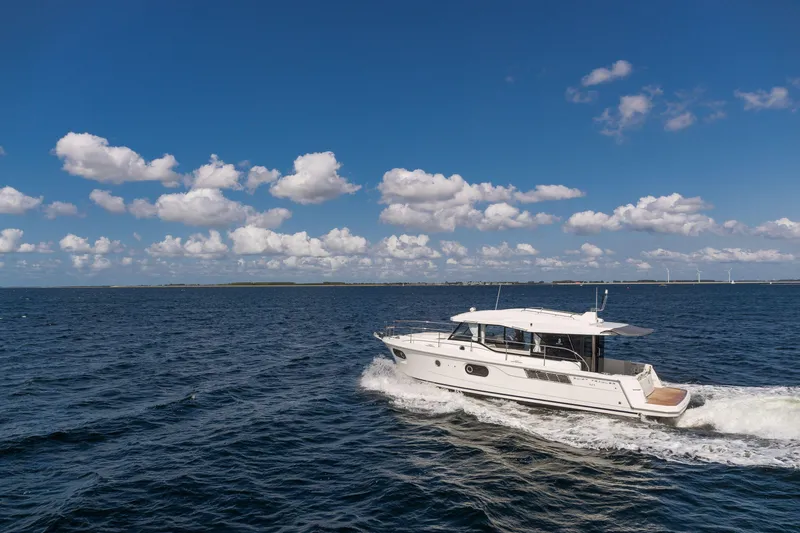 Slide: The Image of 2026 Beneteau Swift Trawler 41 Sedan cruising on open sea under blue sky. - 13