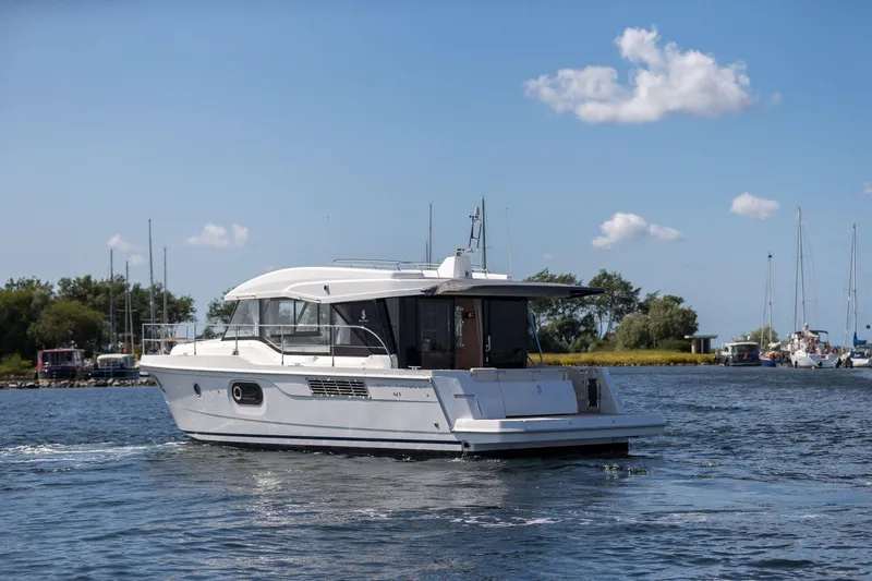 Slide: The Image of 2026 Beneteau Swift Trawler 41 Sedan cruising on a sunny day, surrounded by calm waters. - 2