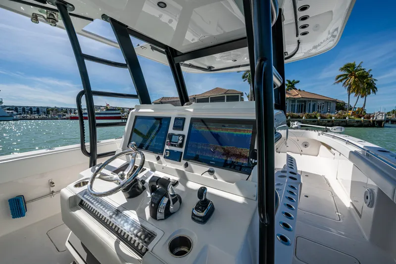 Slide: The Image of 2021 Invincible 40 Catamaran helm with modern controls and navigation screens, docked in sunny marina. - 48