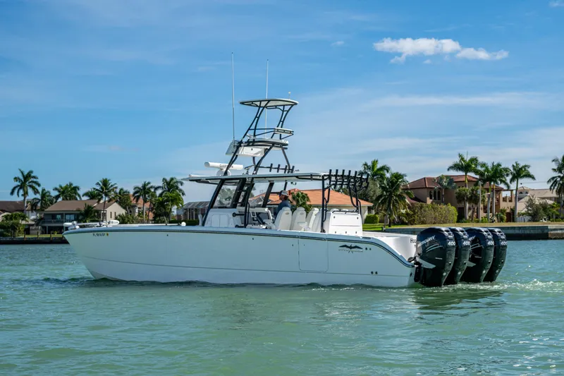 Slide: The Image of 2021 Invincible 40 Catamaran on water, with four outboard engines, near waterfront homes. - 56