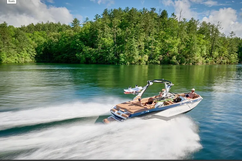 Slide: The Image of 2026 Malibu Wakesetter 21 LX speeding on a scenic lake with lush forest backdrop. - 10