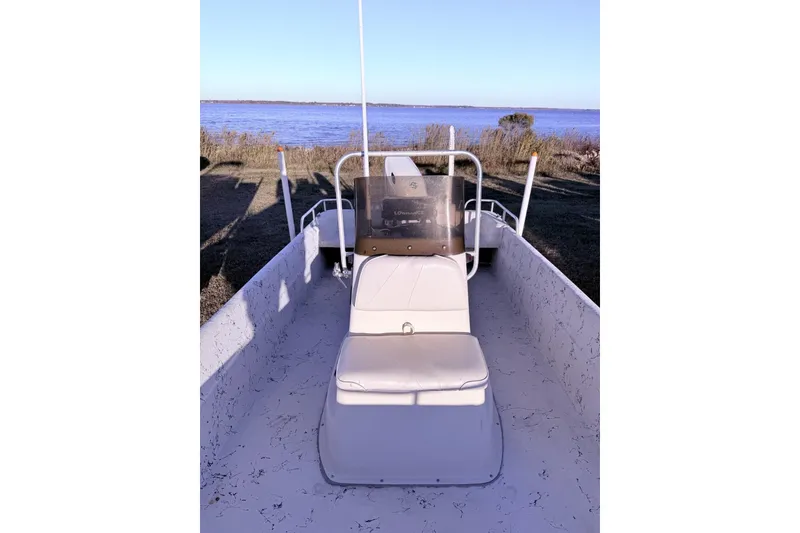 Slide: The Image of 2001 Carolina Skiff 1980 V boat interior with seating, near a serene waterfront. - 8