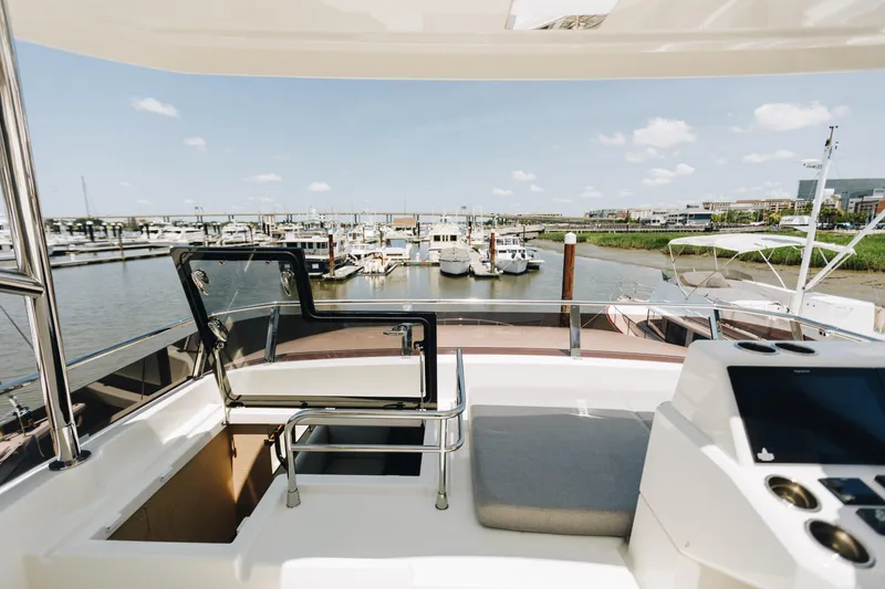 Slide: The Image of Flybridge view from 2024 Beneteau Grand Trawler 62, overlooking marina with boats and clear sky. - 17