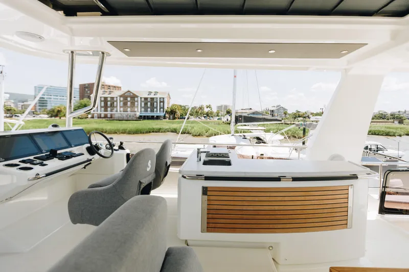 Slide: The Image of 2024 Beneteau Grand Trawler 62 helm and deck area with modern design and waterfront view. - 19