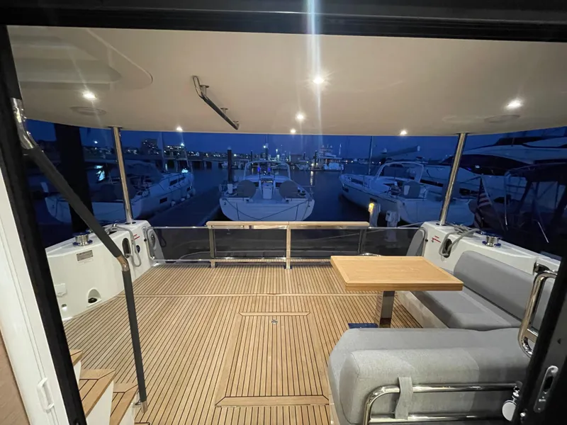 Slide: The Image of 2024 Beneteau Grand Trawler 62 aft deck with seating and table at night. - 21