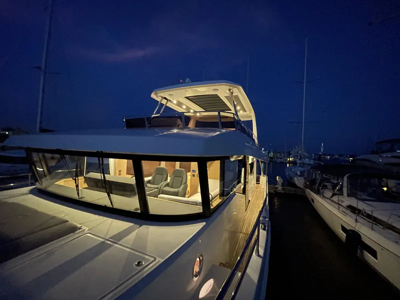 Slide: The Image of 2024 Beneteau Grand Trawler 62 yacht illuminated at night in a marina. - 28