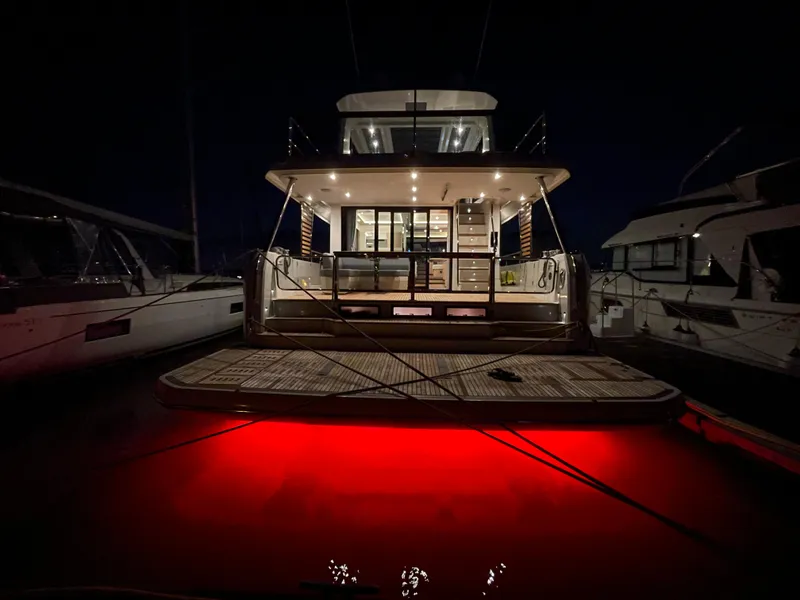 Slide: The Image of 2024 Beneteau Grand Trawler 62 with illuminated deck at night, docked in marina. - 34