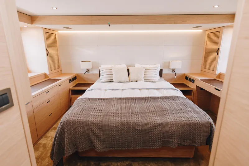 Slide: The Image of Luxurious bedroom interior of 2024 Beneteau Grand Trawler 62 yacht, featuring elegant wood finishes. - 35