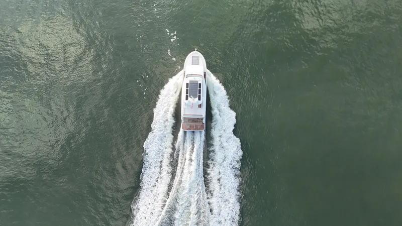 Slide: The Image of Aerial view of 2024 Beneteau Grand Trawler 62 cruising on open water. - 4