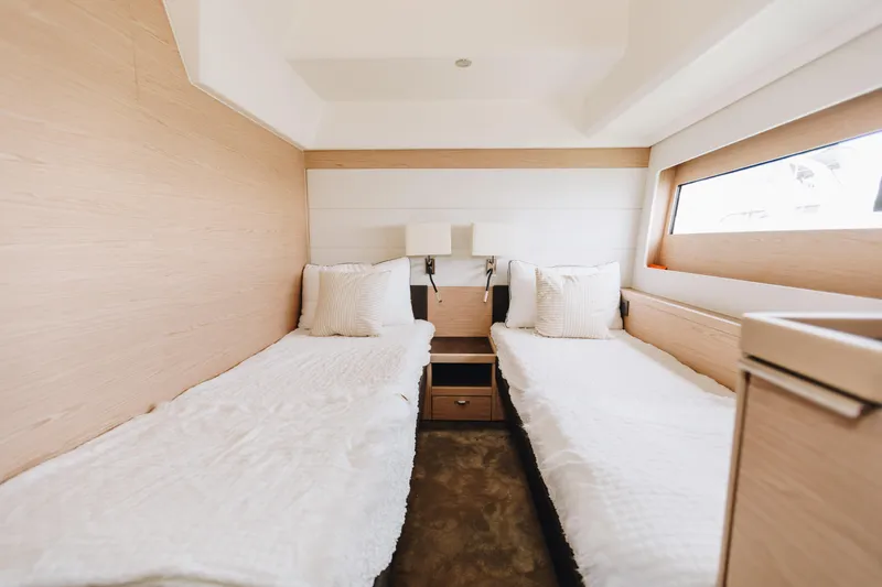 Slide: The Image of 2024 Beneteau Grand Trawler 62 cabin with twin beds and modern decor. - 48