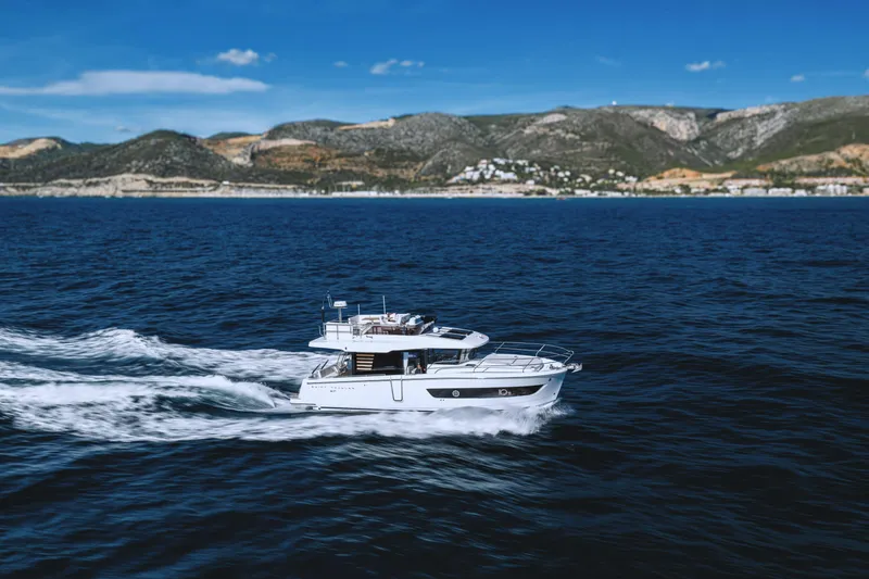 Slide: The Image of 2026 Beneteau Swift Trawler 37 Fly cruising on open sea with scenic coastline backdrop. - 14