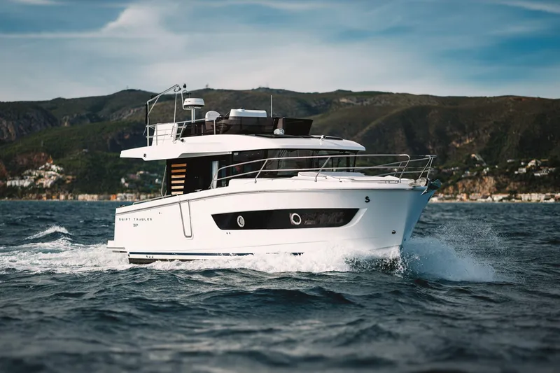 Slide: The Image of 2026 Beneteau Swift Trawler 37 Fly cruising on open water with scenic mountain backdrop. - 16
