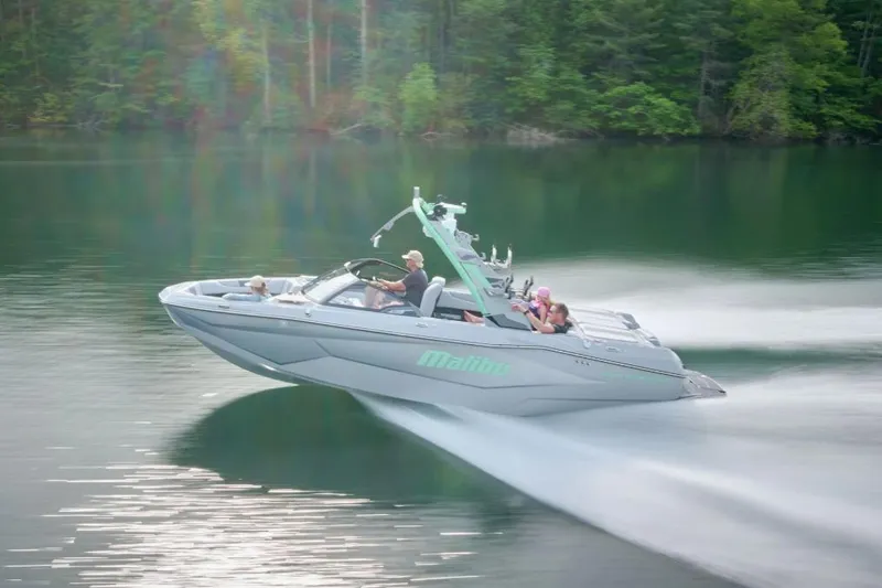 Slide: The Image of 2026 Malibu Wakesetter 22 LSV speeding on a serene lake with lush forest backdrop. - 8