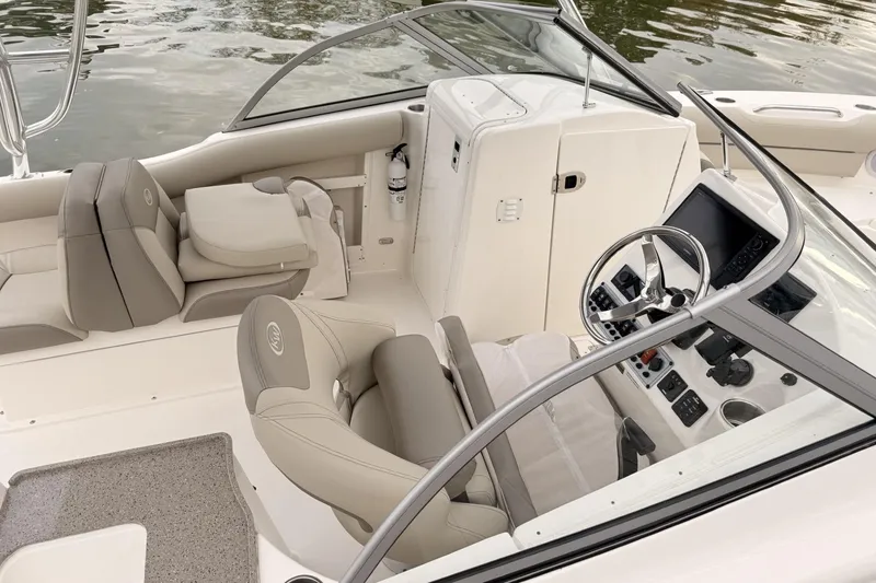 Slide: The Image of 2024 Key West 239 DFS boat interior with steering wheel and seating, on calm water. - 3