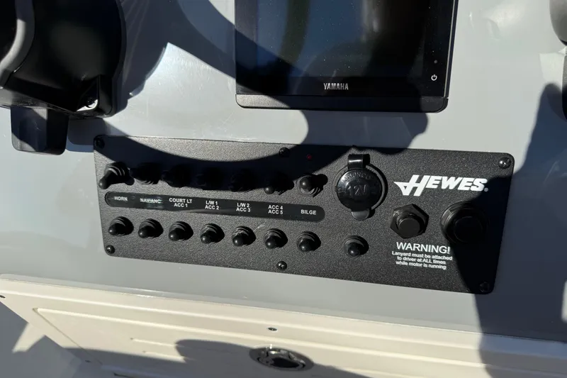 Slide: The Image of Control panel of 2026 Hewes Redfisher 21 boat with switches and warning label. - 11