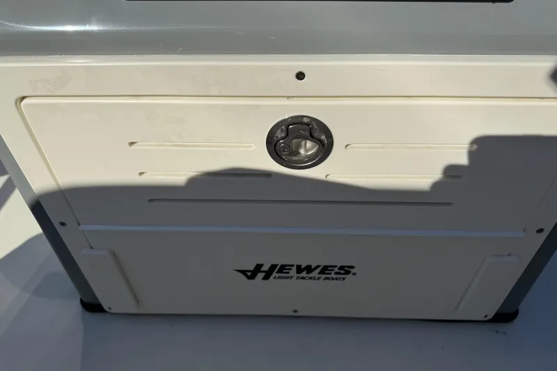 Slide: The Image of 2026 Hewes Redfisher 21 boat compartment with latch and logo in sunlight. - 16