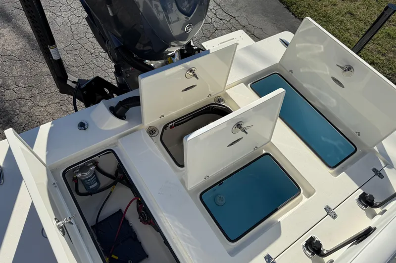 Slide: The Image of 2026 Hewes Redfisher 21 boat with open storage compartments and visible engine. - 24