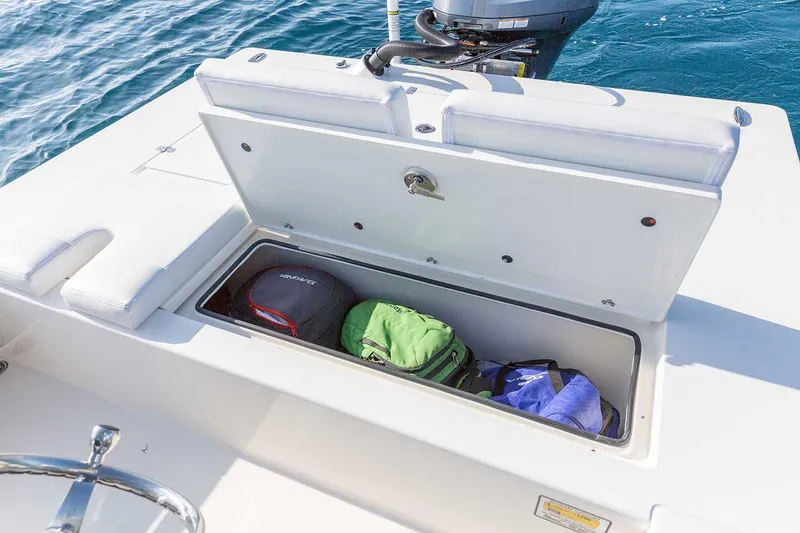 Slide: The Image of Manufacturer Provided Image: 2026 Hewes Redfisher 21 boat storage compartment with gear bags, on calm blue water. - 57