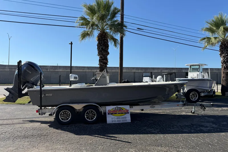 Slide: The Image of 2026 Hewes Redfisher 21 boat on trailer, parked outdoors under clear blue sky. - 58