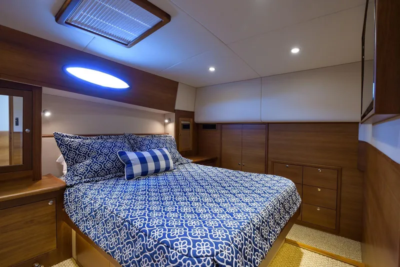 Slide: The Image of Luxurious 2018 Palm Beach Motor Yachts PB55 cabin with striped bedding and wooden cabinetry. - 42