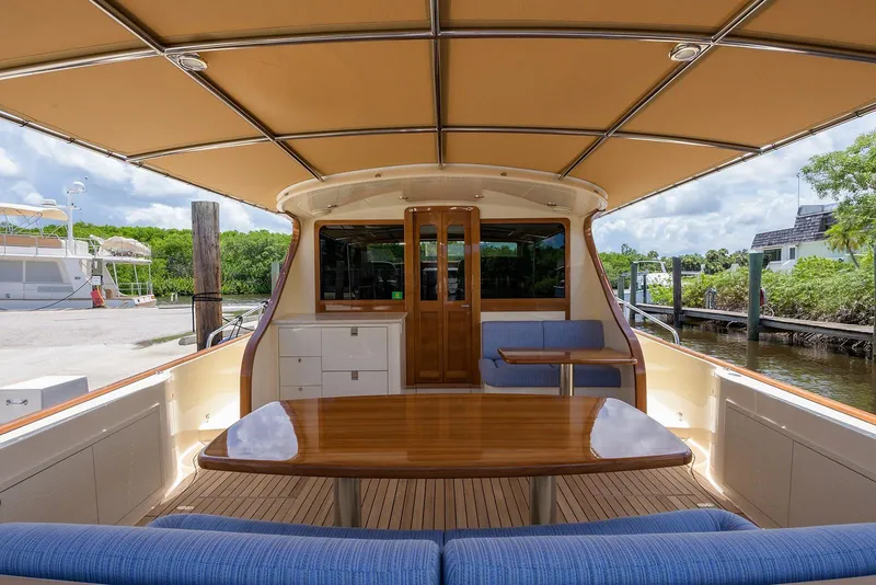 Slide: The Image of 2018 Palm Beach Motor Yachts PB55, luxurious deck with elegant seating and table, waterfront view. - 10