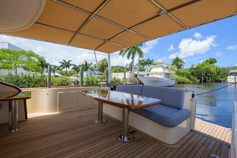Slide: The Image of 2018 Palm Beach Motor Yachts PB55, luxurious deck with seating, table, and scenic waterfront view. - 12