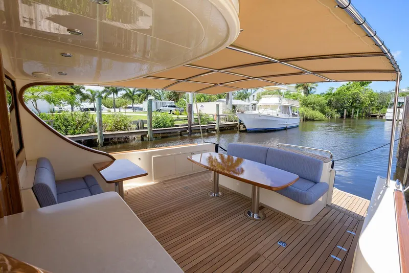 Slide: The Image of 2018 Palm Beach Motor Yachts PB55 deck with tables, overlooking serene waterfront. - 13