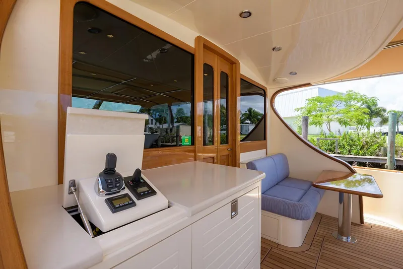 Slide: The Image of 2018 Palm Beach Motor Yachts PB55 aft deck with seating, table, and waterfront view. - 18