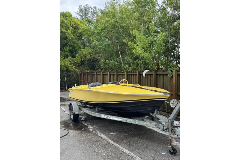 Slide: The Image of Yellow 1987 Donzi 16 Classic boat on trailer, parked near wooden fence and trees. - 3