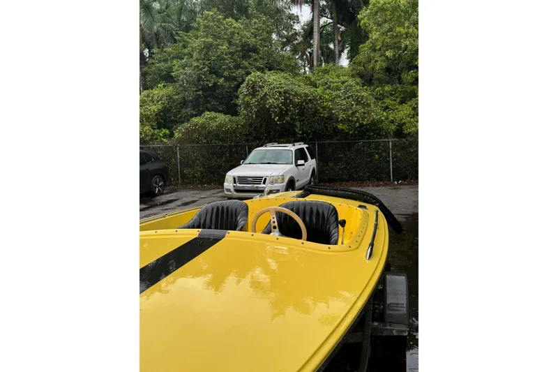 Slide: The Image of Yellow 1987 Donzi 16 Classic boat with black stripes, parked outdoors. - 4