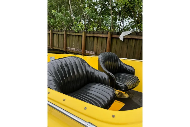 Slide: The Image of Yellow 1987 Donzi 16 Classic boat with black leather seats, wooden fence background. - 5