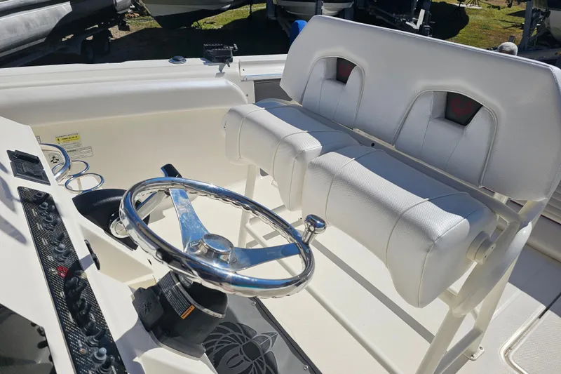 Slide: The Image of 2015 Wellcraft 252 Fisherman boat cockpit with steering wheel and white seating. - 14