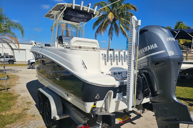 Slide: The Image of 2015 Wellcraft 252 Fisherman boat on trailer, palm trees in background, sunny day. - 2