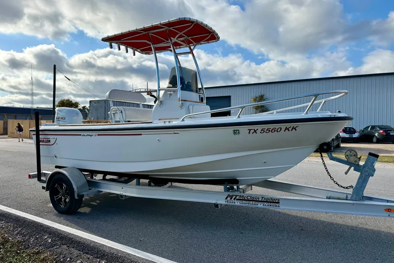 Slide: The Image of 1997 Boston Whaler 17 Outrage II boat on trailer, parked outdoors under cloudy sky. - 4
