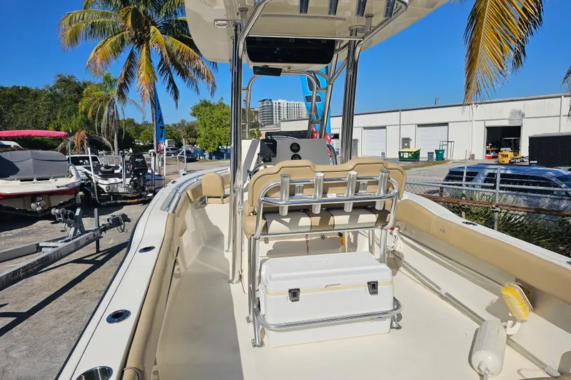 Slide: The Image of 2017 Key West 239 FS boat interior with seating and console, parked near palm trees. - 10