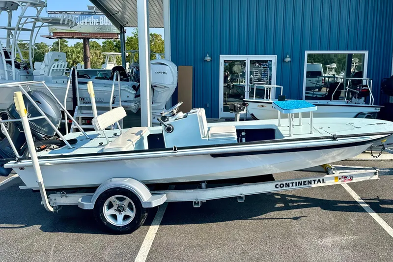 Slide: The Image of 1986 Dolphin 16 SUPER SKIFF boat on a trailer, parked outside a blue building. - 3