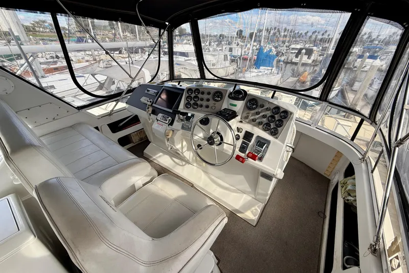 Slide: The Image of 1997 Carver 355 Aft Cabin Motor Yacht helm with controls and marina view. - 11