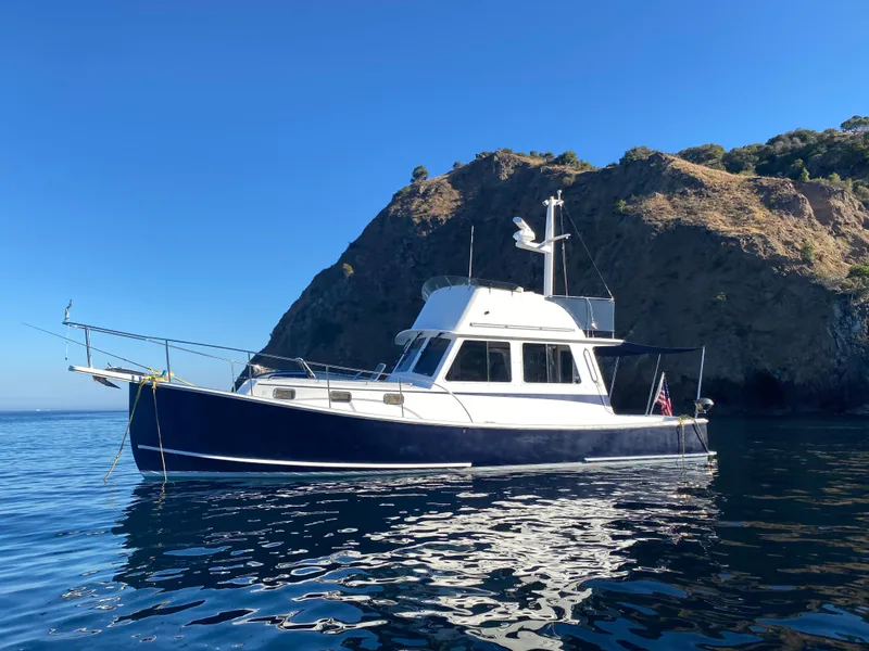 The Image of Northern Bay 36 boat, 2001 model, anchored near a rocky coastline under a clear blue sky. - 0