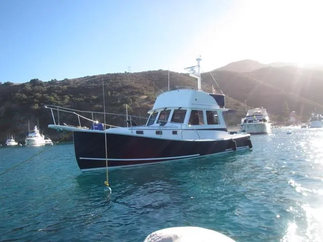 Slide: The Image of 2001 Northern Bay 36 boat anchored in clear blue water with scenic mountain backdrop. - 2